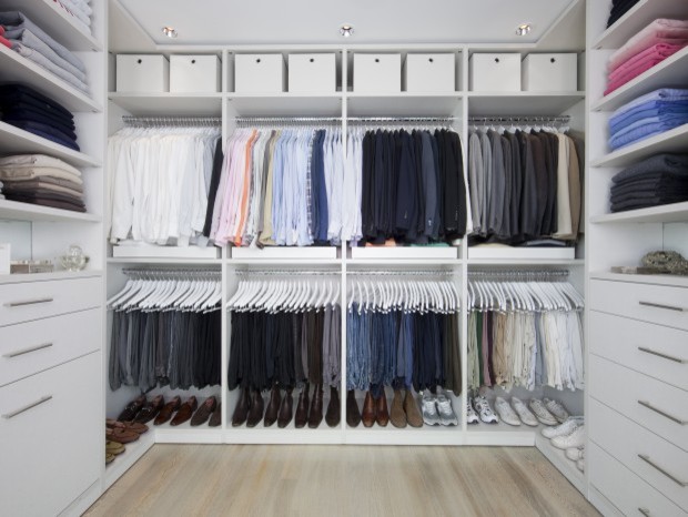 Modern gender neutral walk-in wardrobe in Los Angeles with flat-panel cabinets, white cabinets and light hardwood flooring.