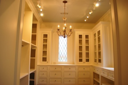Example of a mid-sized tuscan gender-neutral walk-in closet design in Other with white cabinets and beaded inset cabinets