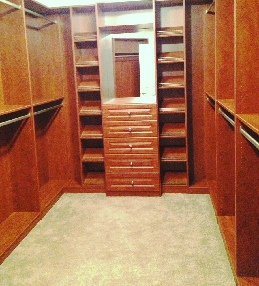 Imagen de armario vestidor unisex tradicional de tamaño medio con armarios con paneles con relieve, puertas de armario de madera oscura y moqueta