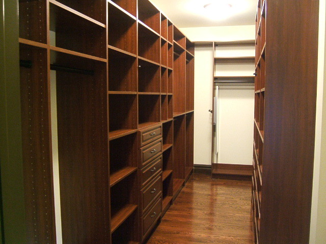 Mittelgroßes, Neutrales Klassisches Ankleidezimmer mit profilierten Schrankfronten, braunen Schränken und braunem Holzboden in New York