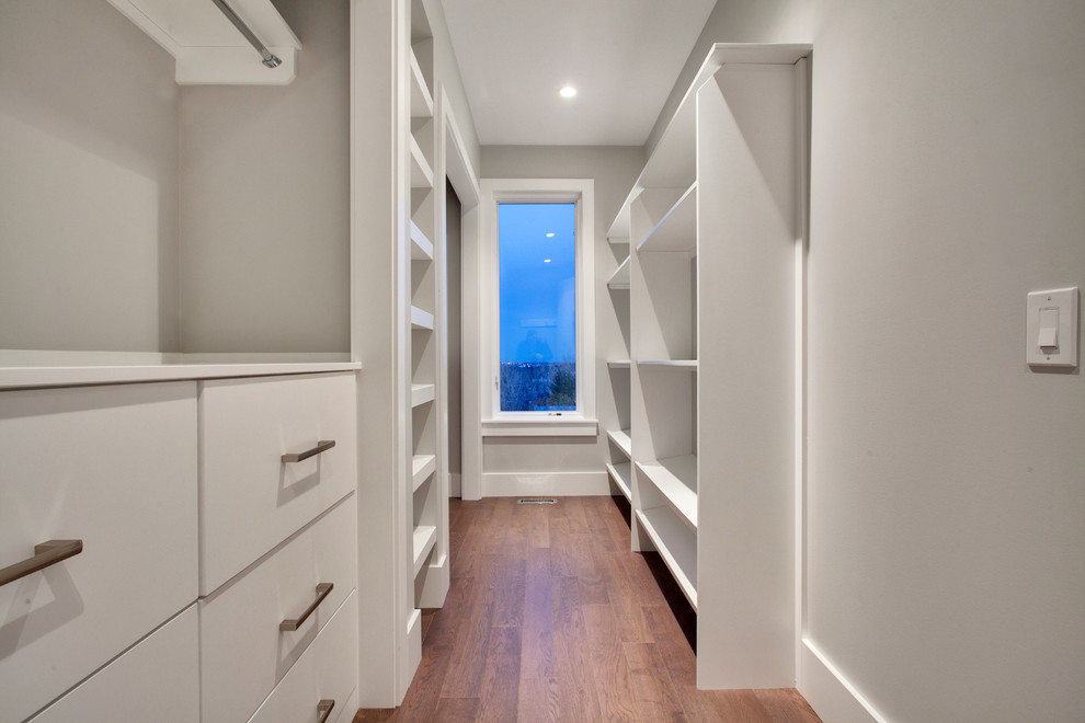 Ispirazione per una piccola cabina armadio unisex minimalista con ante lisce, pavimento in legno massello medio e ante bianche