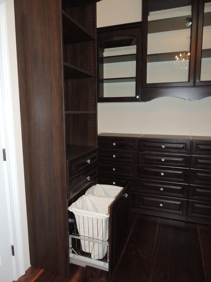 Modelo de armario vestidor unisex tradicional grande con armarios con paneles con relieve, puertas de armario marrones y suelo de madera oscura