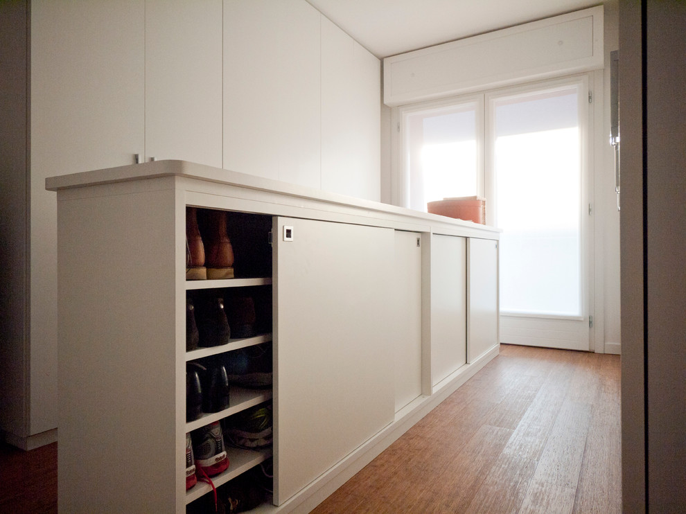 Ejemplo de armario unisex minimalista grande con armarios con paneles lisos, puertas de armario blancas y suelo de bambú