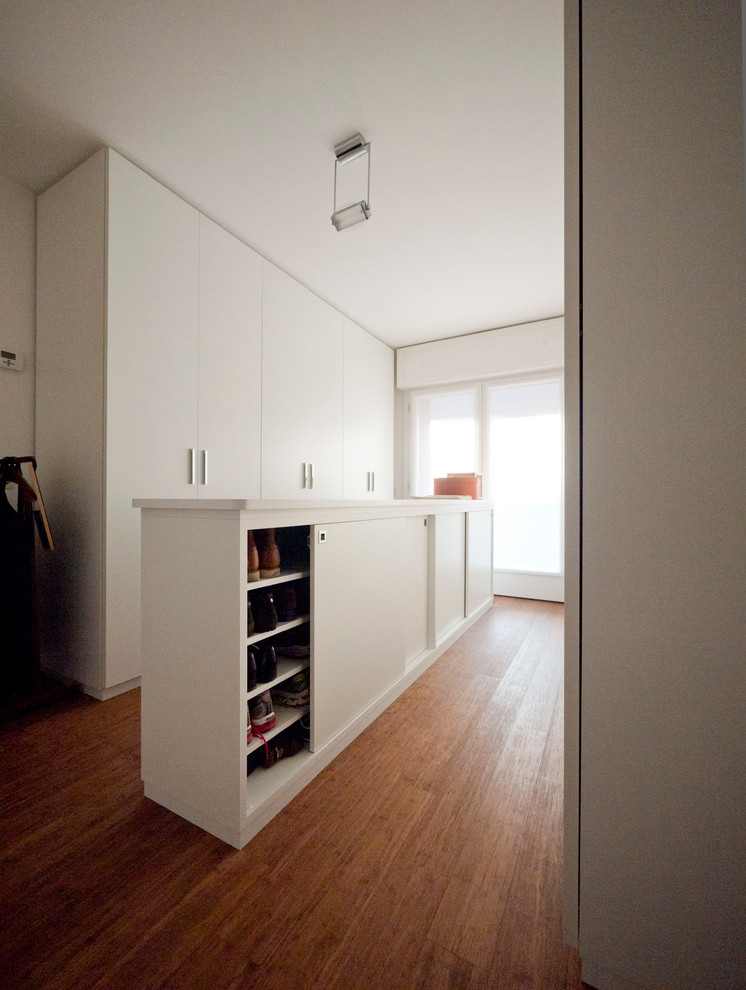 Источник вдохновения для домашнего уюта: большая гардеробная комната унисекс в стиле модернизм с плоскими фасадами, белыми фасадами и полом из бамбука