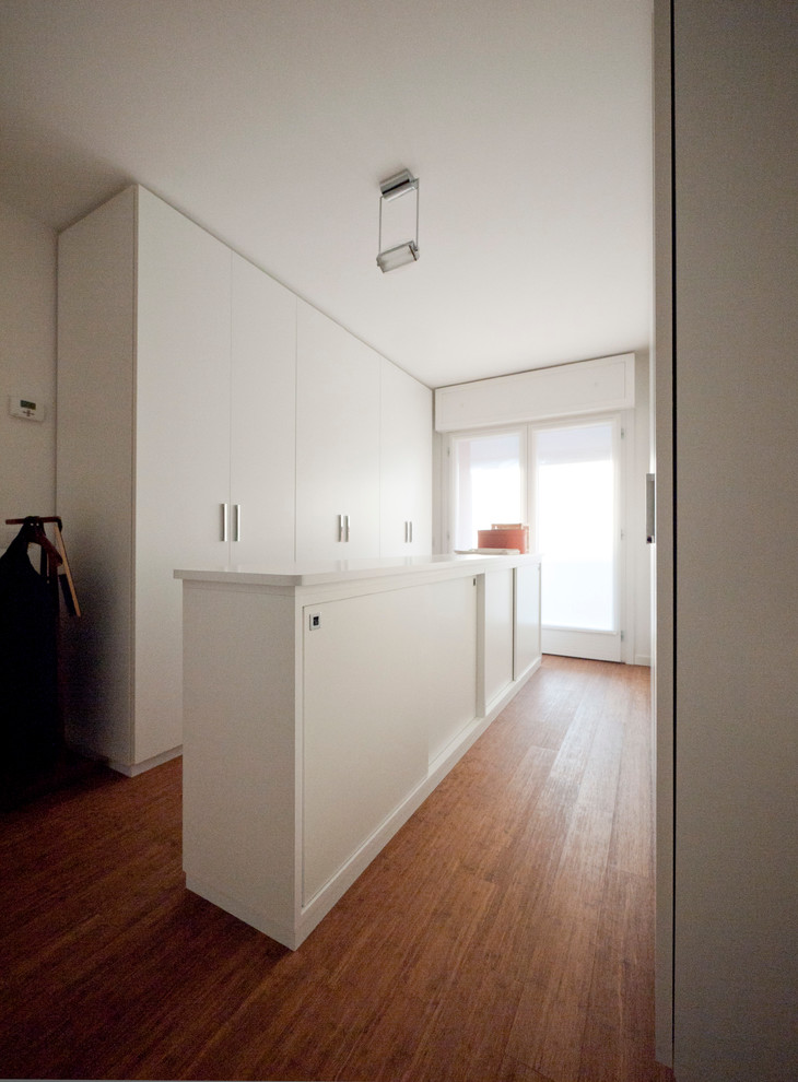 Exemple d'un grand placard dressing moderne neutre avec un placard à porte plane, des portes de placard blanches et parquet en bambou.