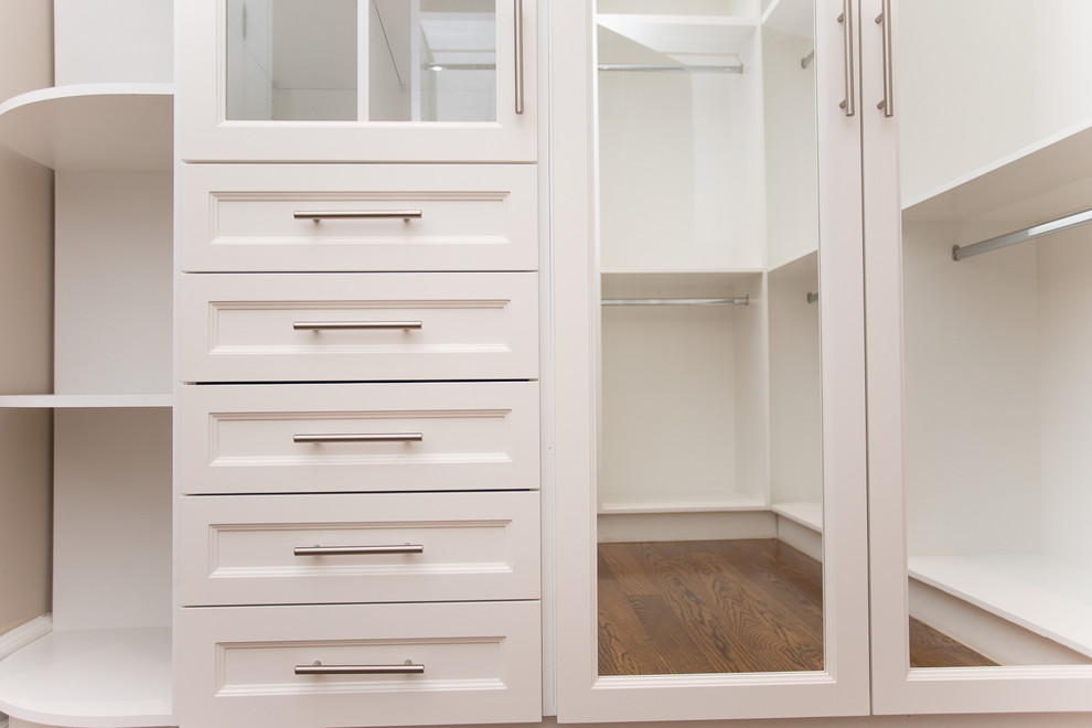 Imagen de vestidor unisex tradicional grande con puertas de armario blancas, suelo de madera oscura y armarios con paneles empotrados