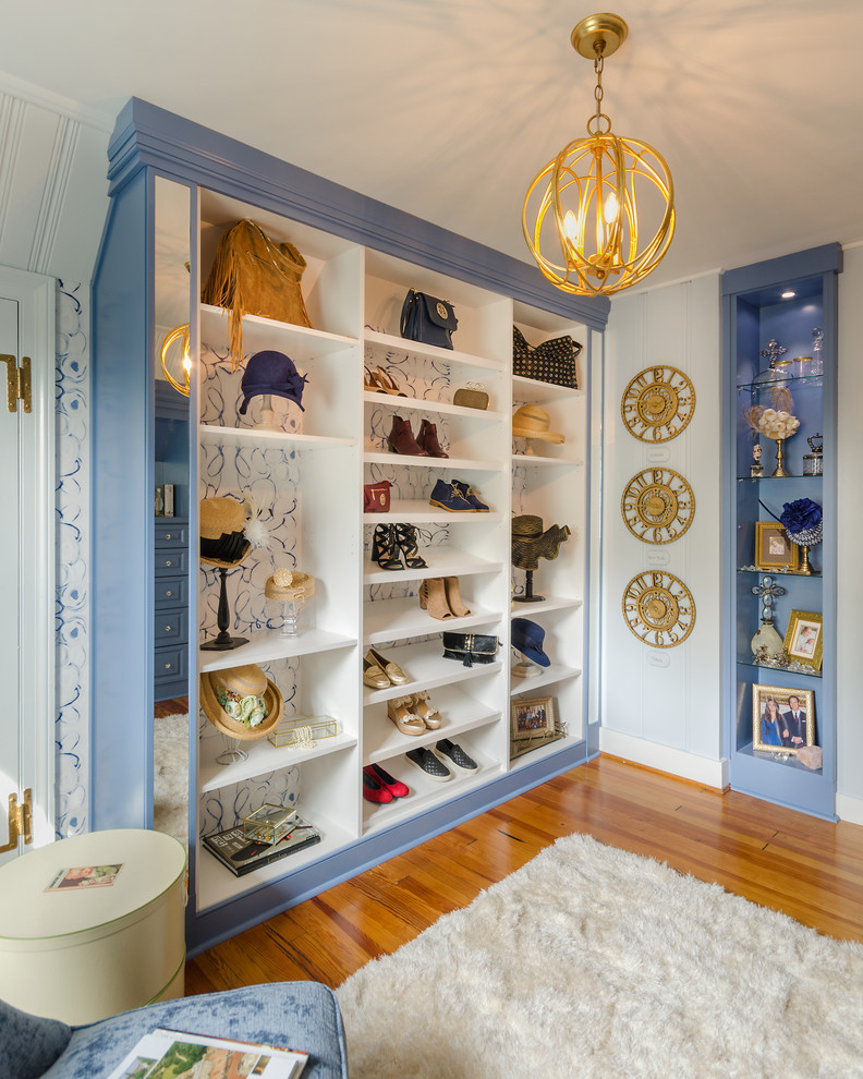 Cette photo montre un dressing room chic pour une femme avec des portes de placard bleues, un placard sans porte et un sol en bois brun.