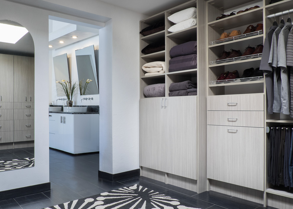 Imagen de armario vestidor unisex moderno grande con armarios con paneles lisos, puertas de armario de madera clara, suelo de baldosas de porcelana y suelo negro