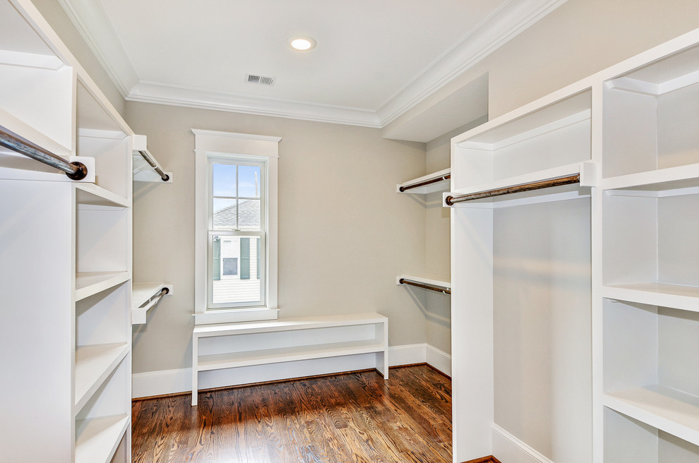 Inspiration for a medium sized traditional gender neutral walk-in wardrobe in DC Metro with dark hardwood flooring, medium wood cabinets and brown floors.