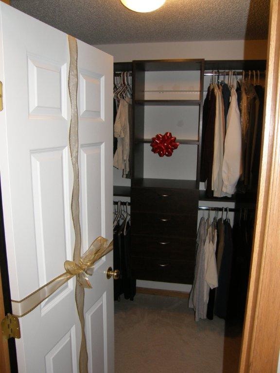 Klassisk inredning av ett mellanstort walk-in-closet, med släta luckor, svarta skåp, heltäckningsmatta och beiget golv
