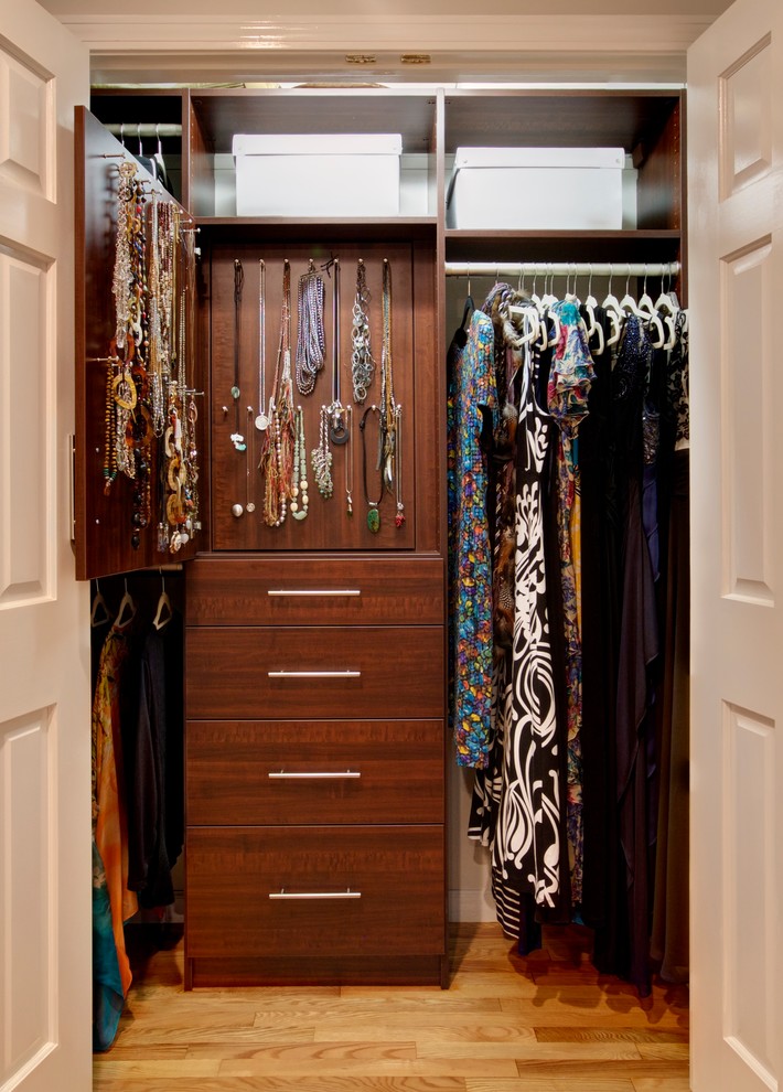Inspiration for a small transitional gender-neutral medium tone wood floor and brown floor reach-in closet remodel in New York with flat-panel cabinets and dark wood cabinets