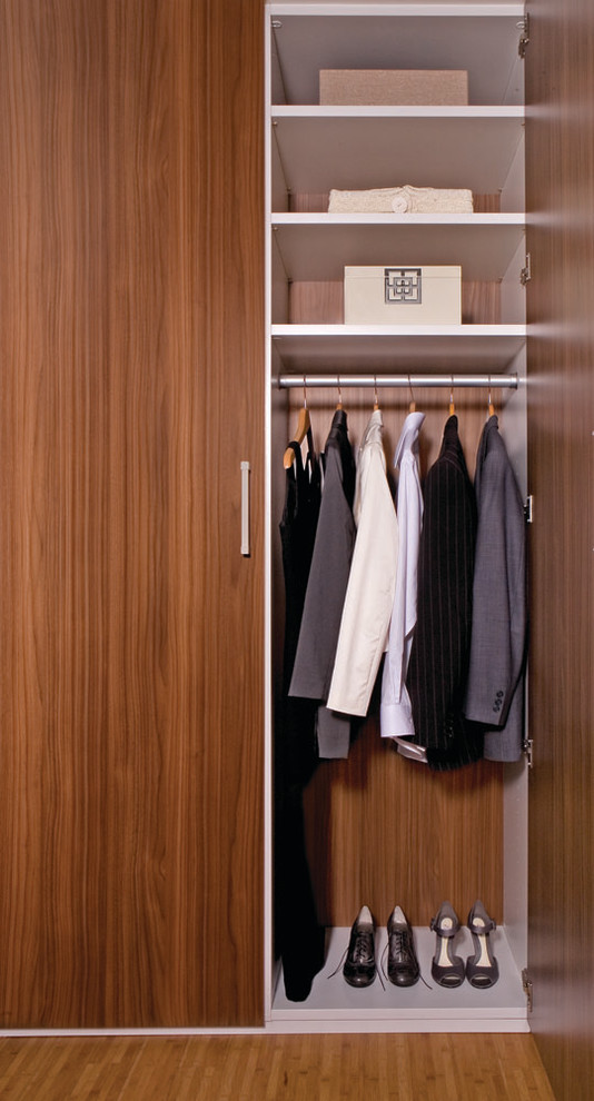 Cette image montre un placard dressing traditionnel en bois brun neutre et de taille moyenne avec un sol en bois brun et un placard à porte plane.