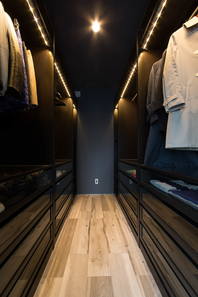 Bild på en funkis garderob för män, med svarta skåp, ljust trägolv och beiget golv