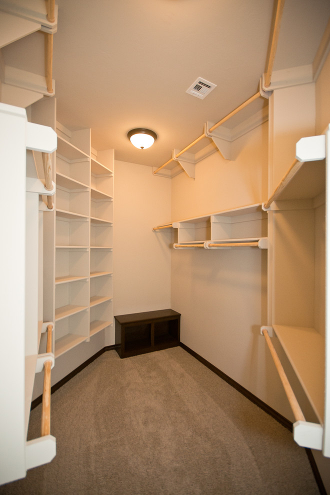 Example of a mid-sized classic gender-neutral carpeted walk-in closet design in Oklahoma City with open cabinets and beige cabinets