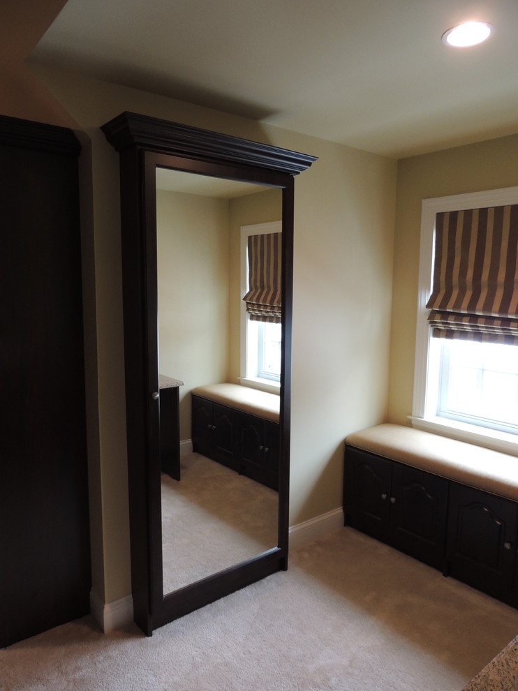Photo of a large traditional gender neutral walk-in wardrobe in Philadelphia with raised-panel cabinets and dark wood cabinets.