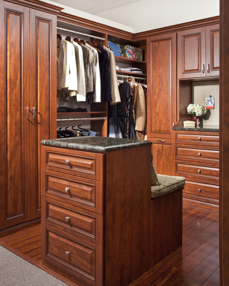Imagen de armario vestidor clásico con armarios con paneles con relieve, puertas de armario de madera en tonos medios y suelo de madera oscura