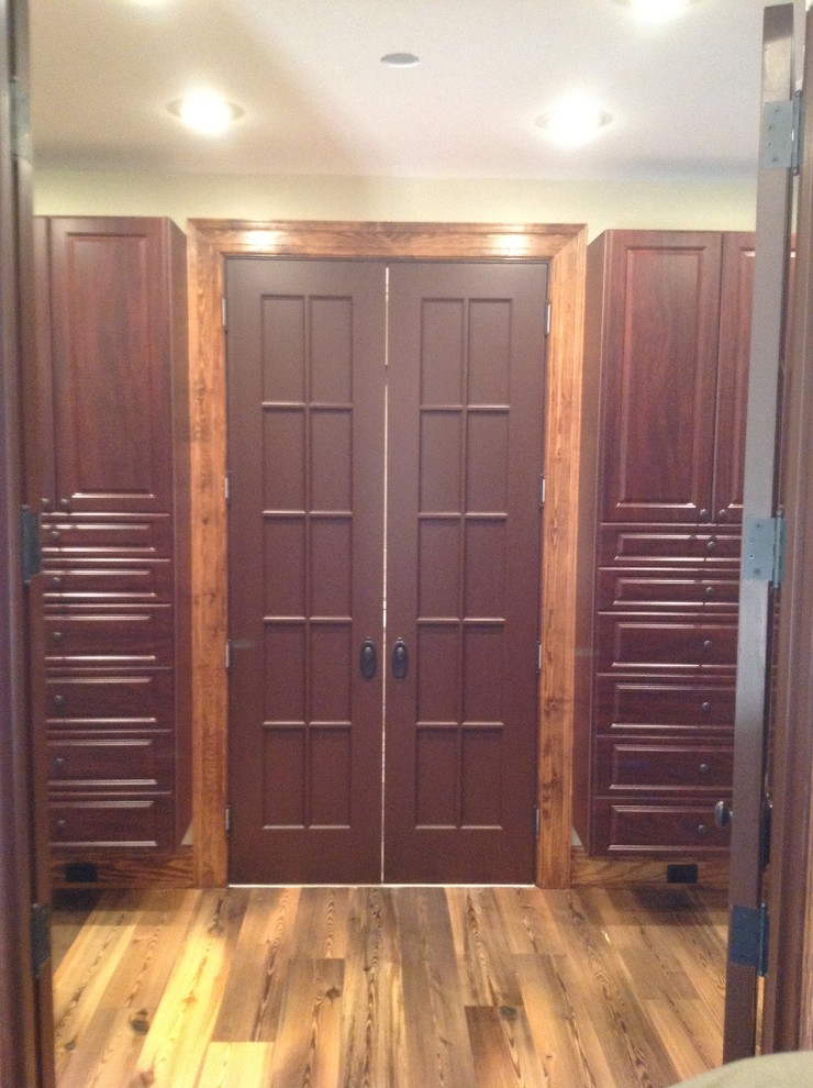 Idée de décoration pour un dressing en bois foncé de taille moyenne et neutre avec un placard avec porte à panneau surélevé et un sol en bois brun.