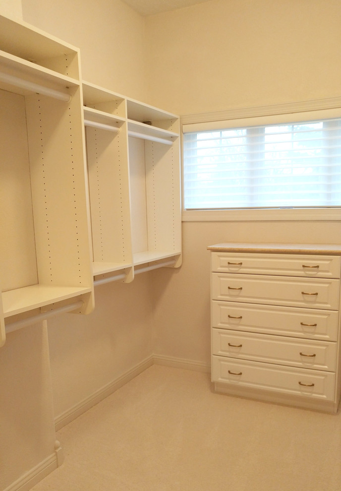 Foto de armario vestidor unisex clásico con puertas de armario blancas, moqueta y suelo beige