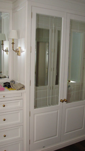 Diseño de vestidor unisex moderno de tamaño medio con armarios abiertos, suelo de madera en tonos medios y puertas de armario blancas