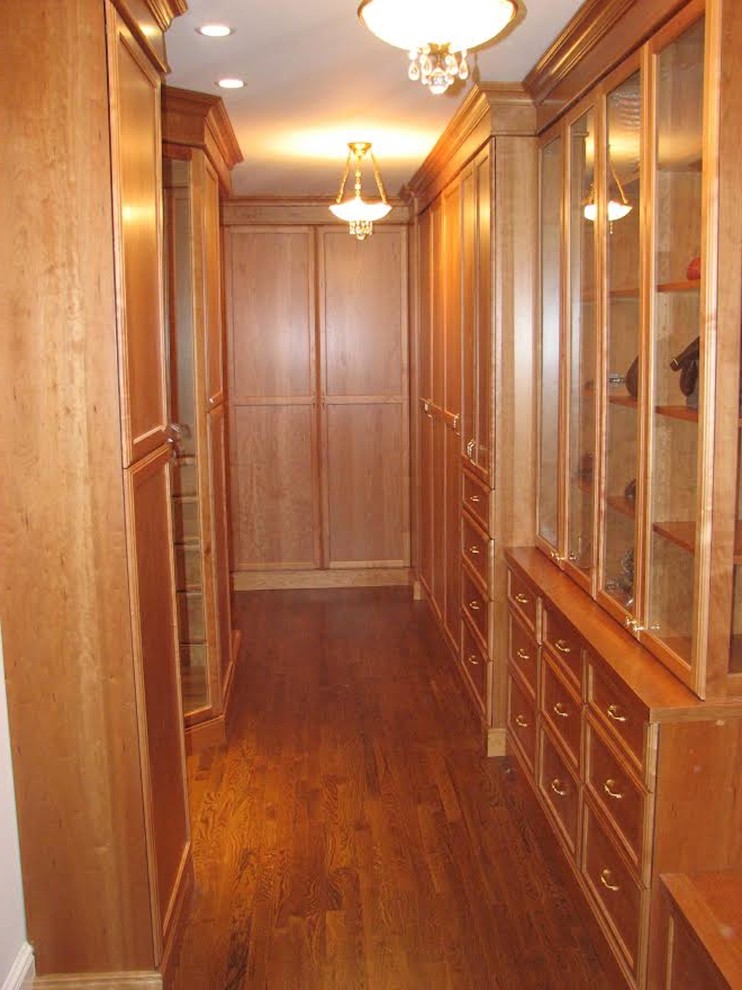 Ejemplo de vestidor unisex clásico de tamaño medio con armarios abiertos, puertas de armario con efecto envejecido y suelo de madera en tonos medios