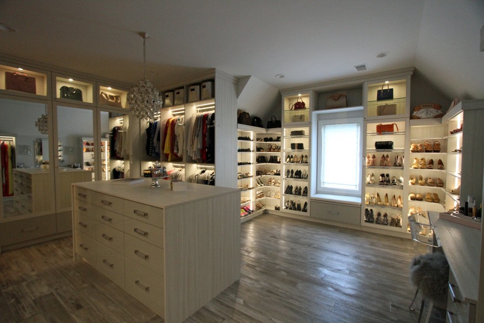 Diseño de armario vestidor actual grande con armarios con paneles lisos, puertas de armario de madera clara, suelo de madera en tonos medios y suelo marrón