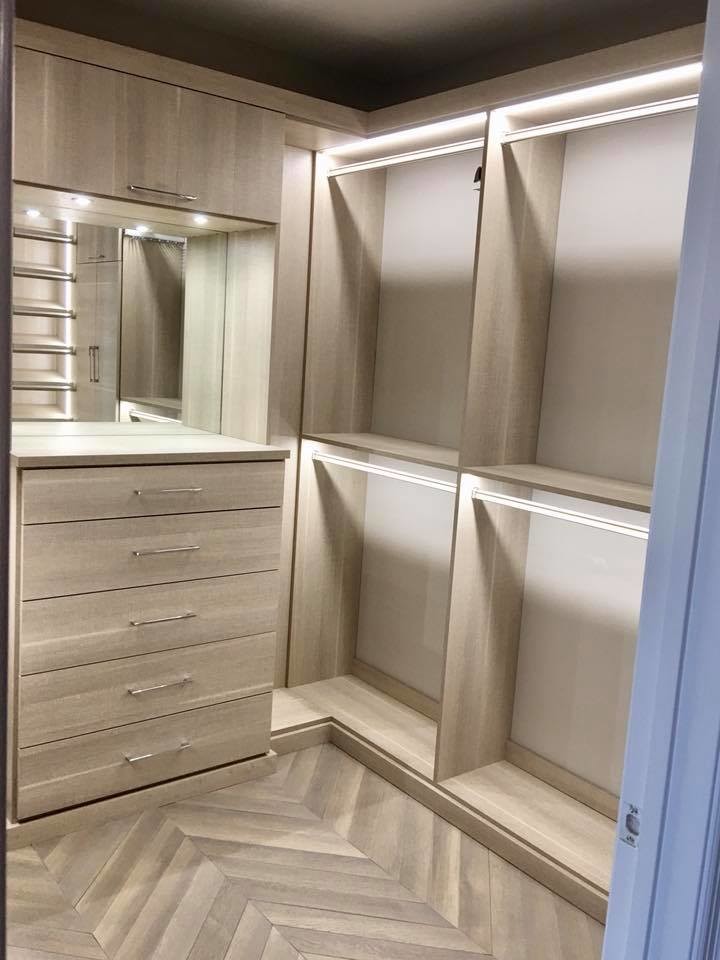 Modelo de armario vestidor unisex contemporáneo de tamaño medio con armarios con paneles lisos, puertas de armario de madera oscura, suelo de madera en tonos medios y suelo multicolor