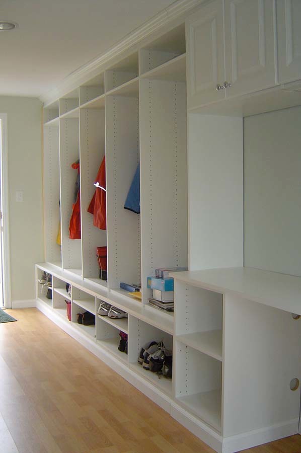 This is an example of a medium sized traditional gender neutral standard wardrobe in New York with white cabinets and light hardwood flooring.