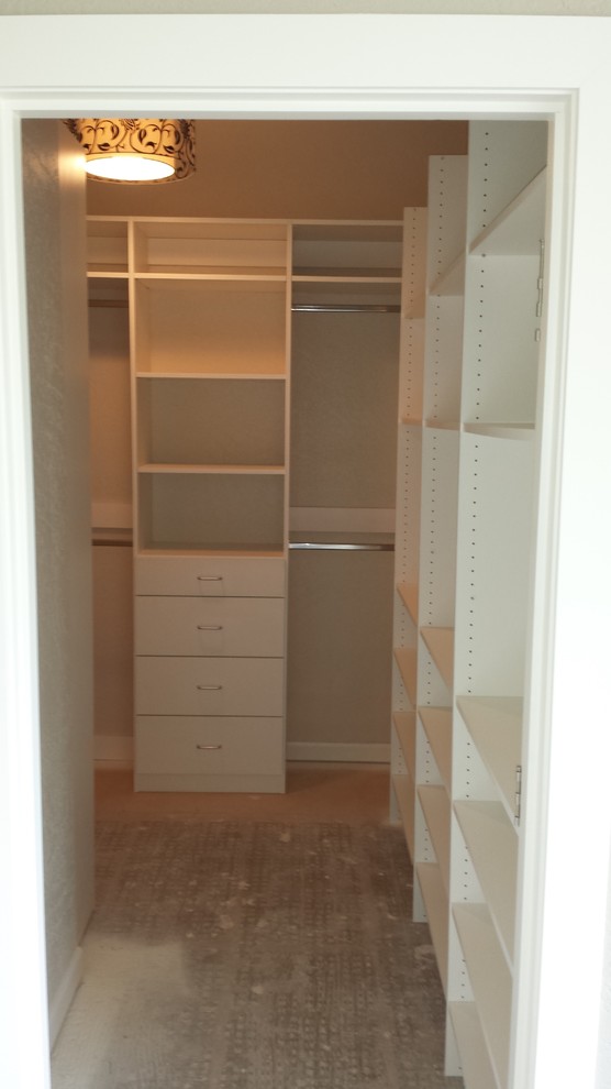 Example of a mid-sized gender-neutral carpeted walk-in closet design in Other with flat-panel cabinets and white cabinets