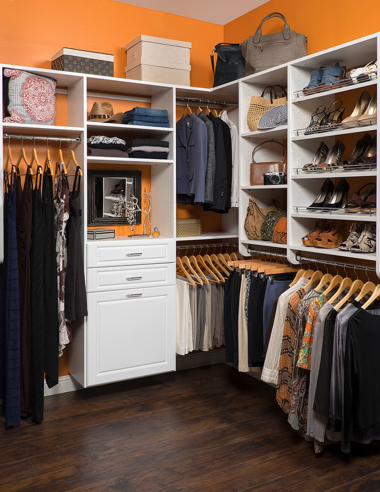 Ejemplo de armario vestidor unisex clásico de tamaño medio con armarios con paneles con relieve, puertas de armario blancas y suelo de madera en tonos medios