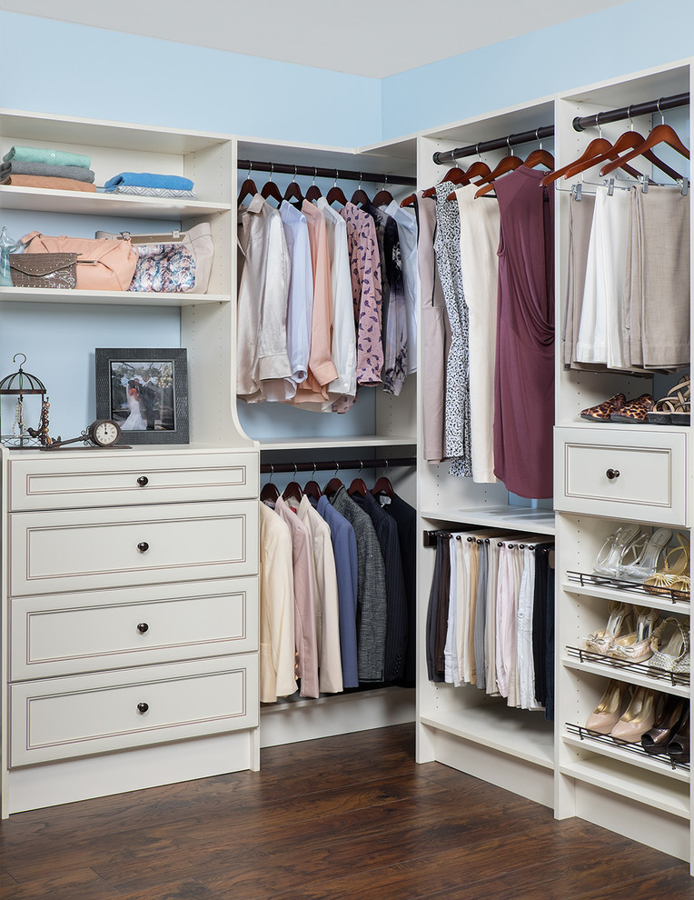 Aménagement d'un dressing classique de taille moyenne et neutre avec un placard à porte affleurante, des portes de placard blanches et un sol en bois brun.