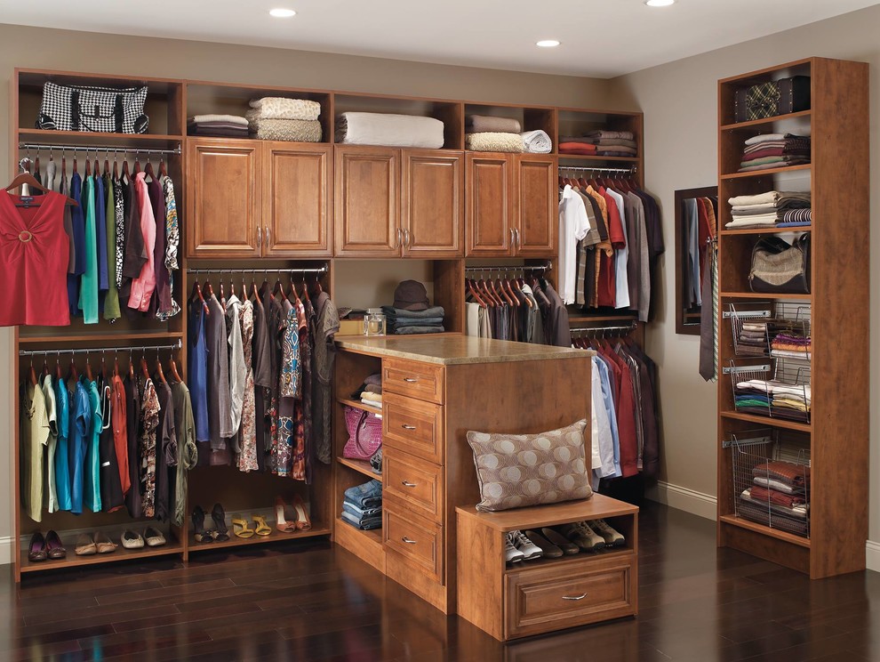 Photo of a large traditional gender neutral dressing room in Other with raised-panel cabinets, dark wood cabinets, dark hardwood flooring and brown floors.