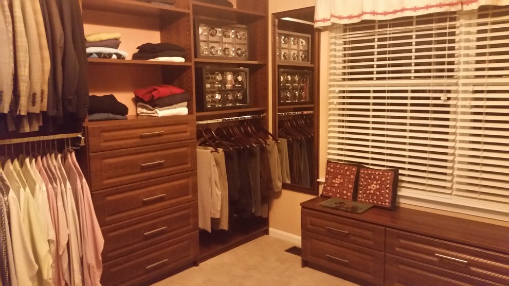 Diseño de armario vestidor unisex tradicional de tamaño medio con armarios con paneles con relieve, puertas de armario de madera oscura y moqueta