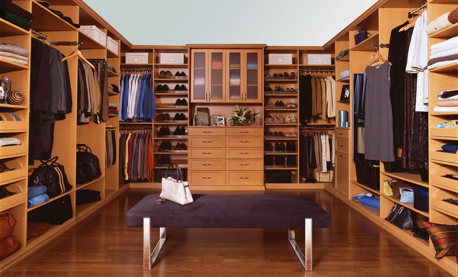 Diseño de vestidor unisex tradicional grande con armarios con paneles empotrados, puertas de armario de madera oscura y suelo de madera en tonos medios