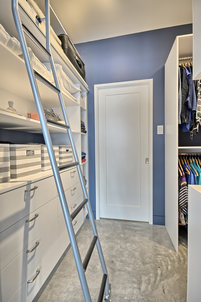 Foto de armario vestidor unisex tradicional pequeño con armarios con paneles lisos, puertas de armario blancas y suelo de cemento