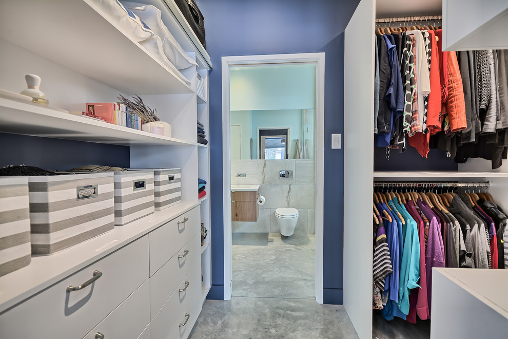 Modelo de armario vestidor unisex clásico pequeño con armarios con paneles lisos, puertas de armario blancas y suelo de cemento