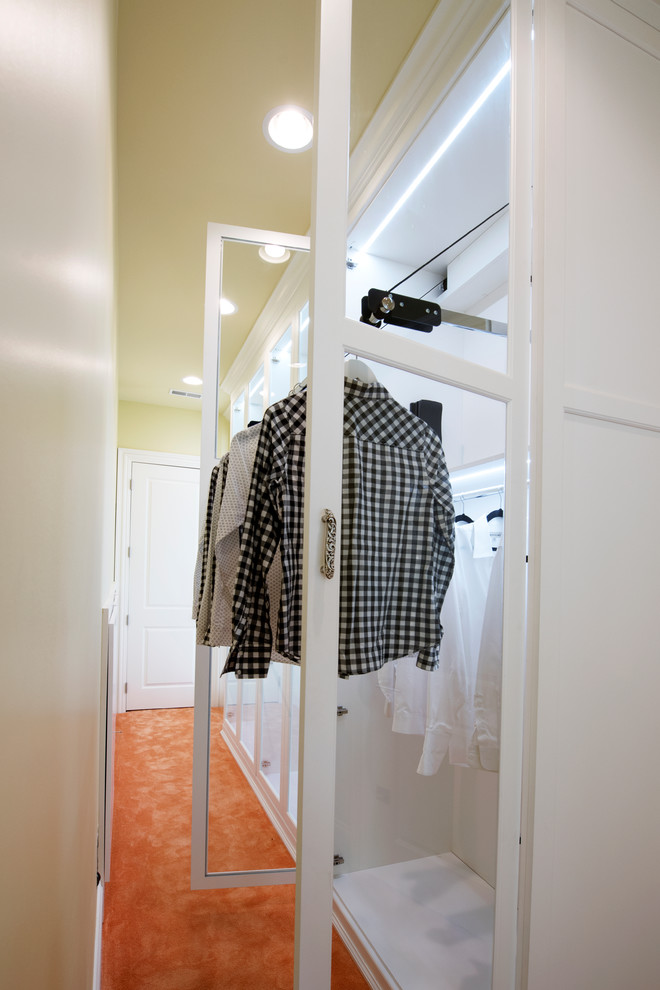 Ejemplo de armario vestidor de mujer clásico renovado extra grande con armarios tipo vitrina, puertas de armario blancas y moqueta