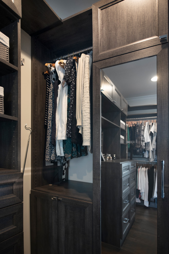 Ejemplo de armario vestidor unisex tradicional renovado de tamaño medio con armarios con paneles empotrados, puertas de armario con efecto envejecido, suelo de madera oscura y suelo marrón