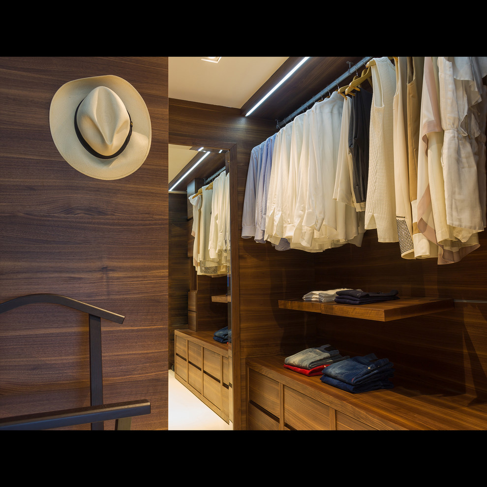 Immagine di una cabina armadio unisex minimalista di medie dimensioni con ante lisce, ante in legno scuro e pavimento beige