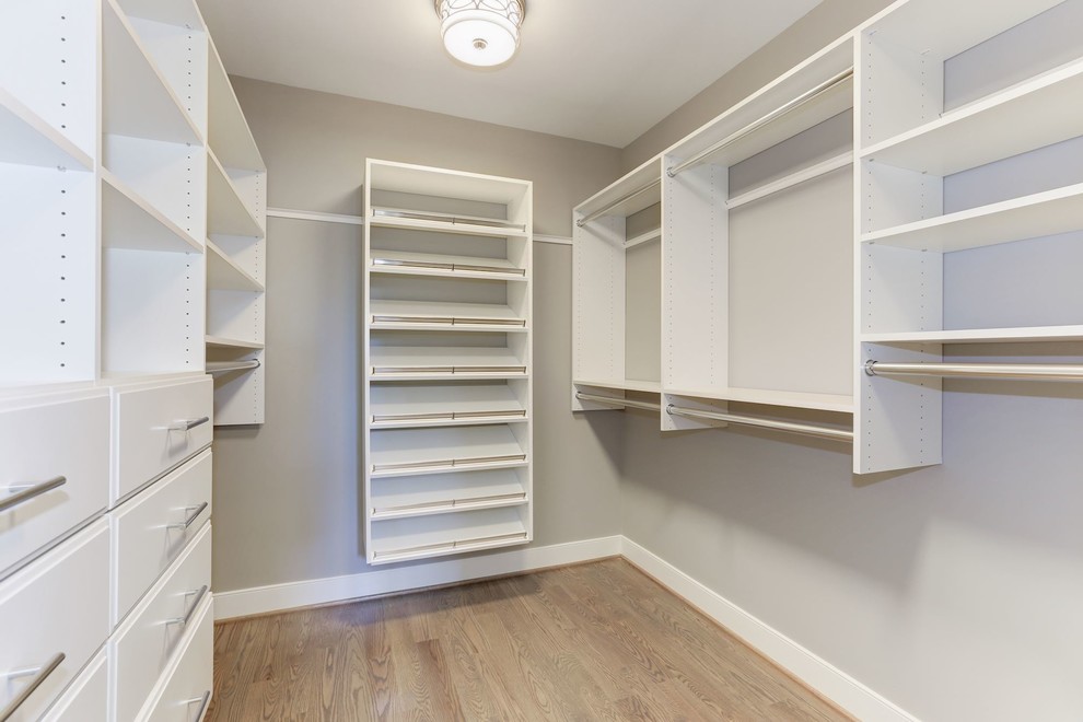 This is an example of a medium sized classic gender neutral walk-in wardrobe in Other with open cabinets, white cabinets, light hardwood flooring and brown floors.