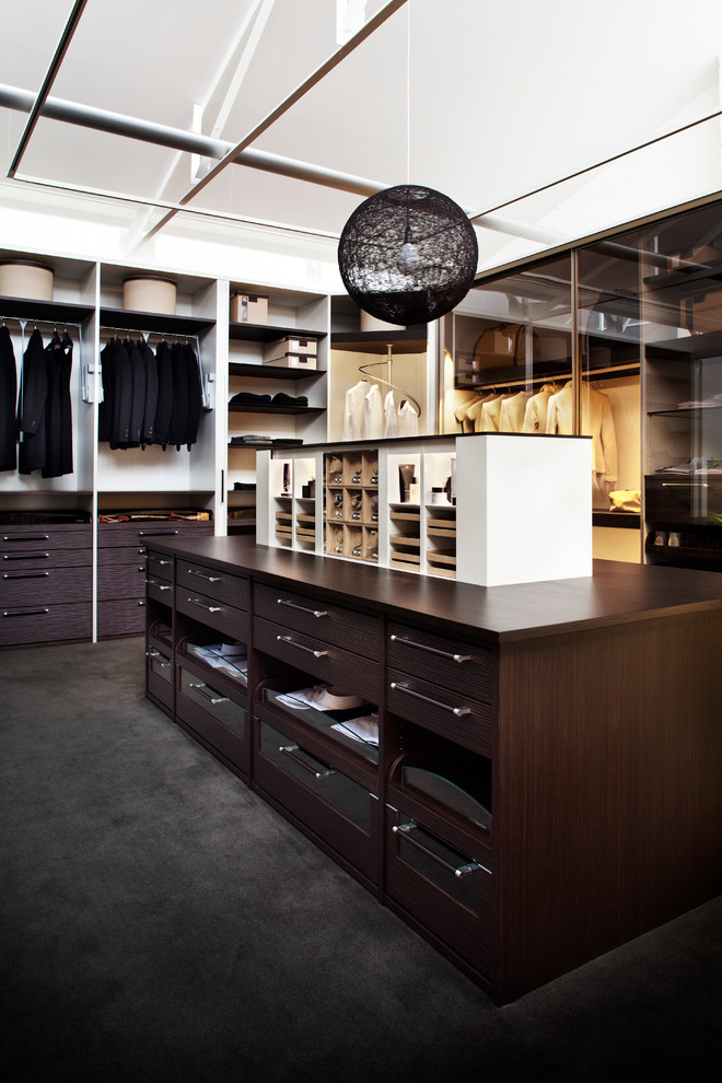 На фото: гардеробная комната среднего размера, унисекс в современном стиле с темными деревянными фасадами, ковровым покрытием, открытыми фасадами и черным полом