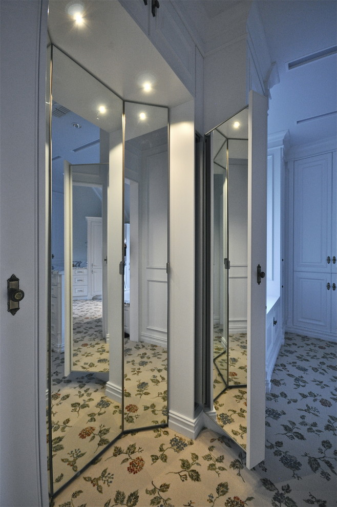 Diseño de vestidor unisex clásico grande con armarios con paneles lisos, puertas de armario blancas y moqueta