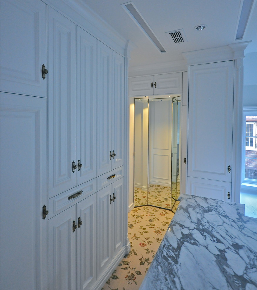 Foto de vestidor unisex clásico grande con armarios con paneles lisos, puertas de armario blancas y moqueta