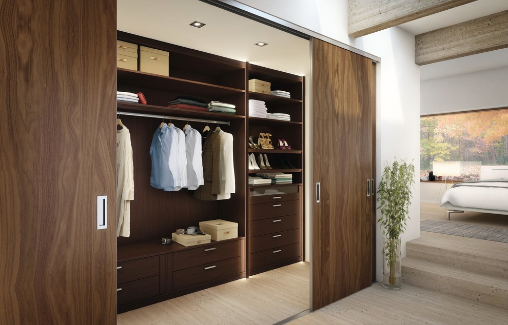 Foto de armario vestidor unisex actual de tamaño medio con armarios con paneles lisos, puertas de armario de madera en tonos medios y suelo de madera clara