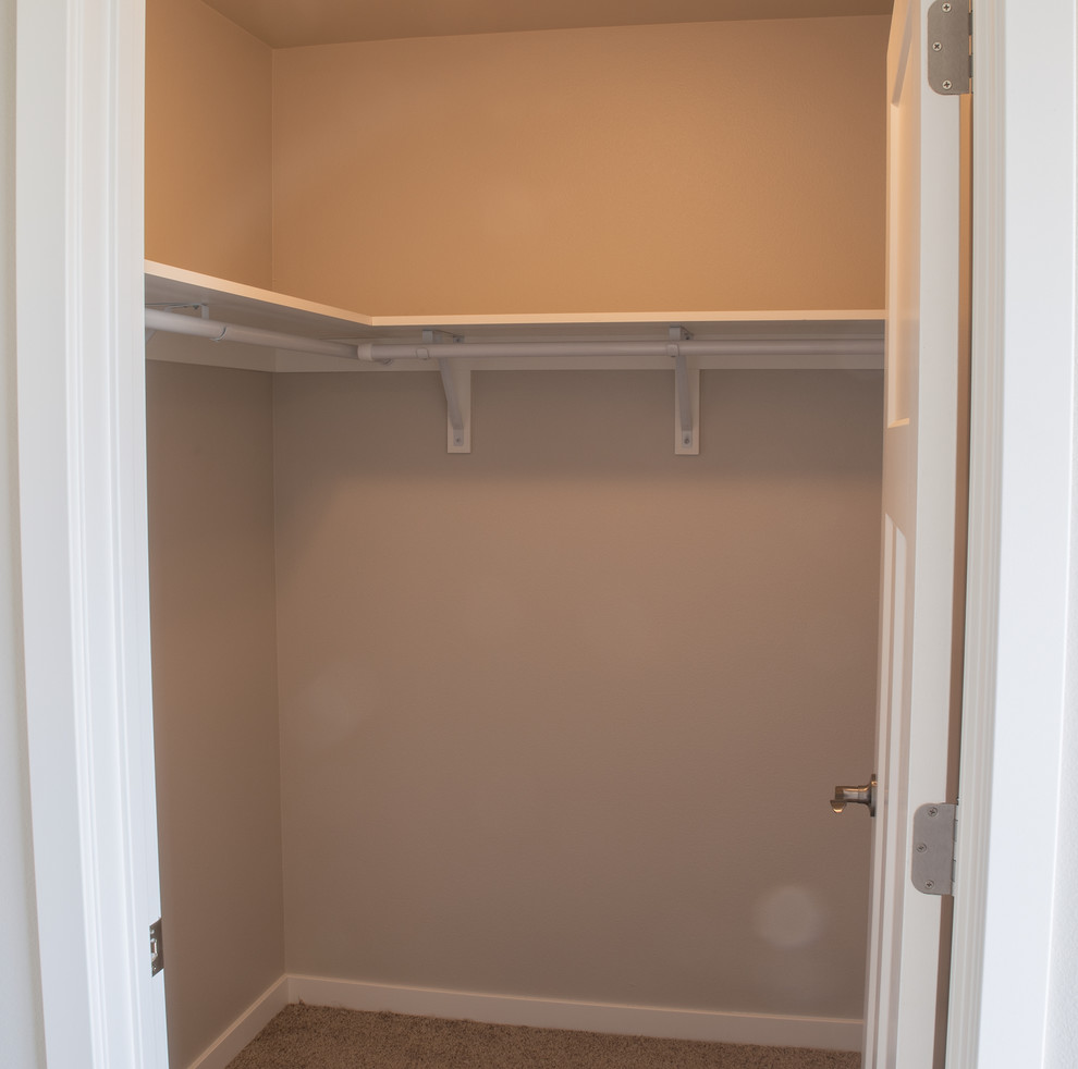 На фото: маленькая гардеробная комната унисекс в стиле неоклассика (современная классика) с ковровым покрытием и коричневым полом для на участке и в саду с