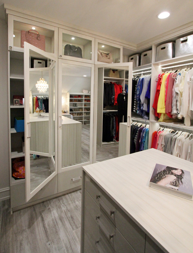 Example of a large transitional women's light wood floor and gray floor walk-in closet design in Detroit with glass-front cabinets and light wood cabinets