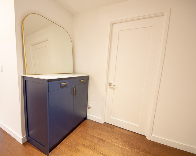 Ispirazione per una cabina armadio unisex contemporanea di medie dimensioni con ante lisce, ante blu, pavimento in legno massello medio e pavimento marrone