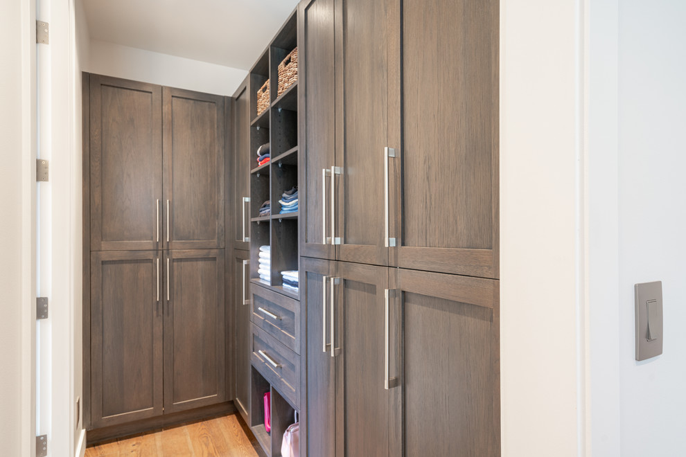 Imagen de armario vestidor unisex minimalista de tamaño medio con armarios estilo shaker, puertas de armario marrones, suelo de madera en tonos medios y suelo marrón