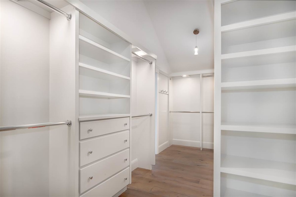 Imagen de armario vestidor de estilo americano grande con armarios abiertos, puertas de armario blancas y suelo de madera en tonos medios