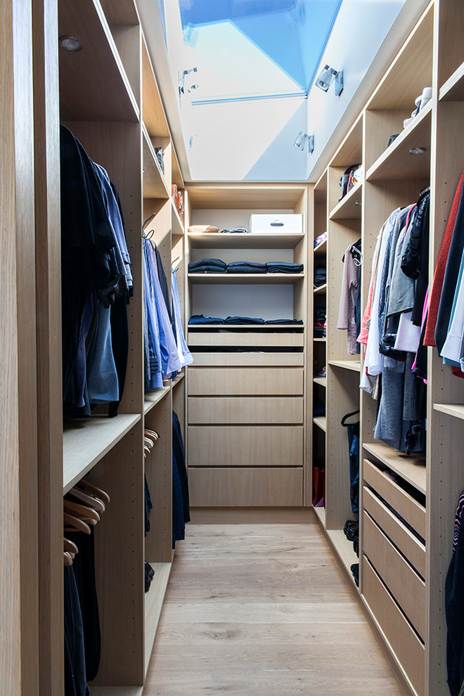Imagen de armario vestidor de hombre contemporáneo de tamaño medio con armarios con paneles lisos, puertas de armario de madera clara y suelo de madera clara