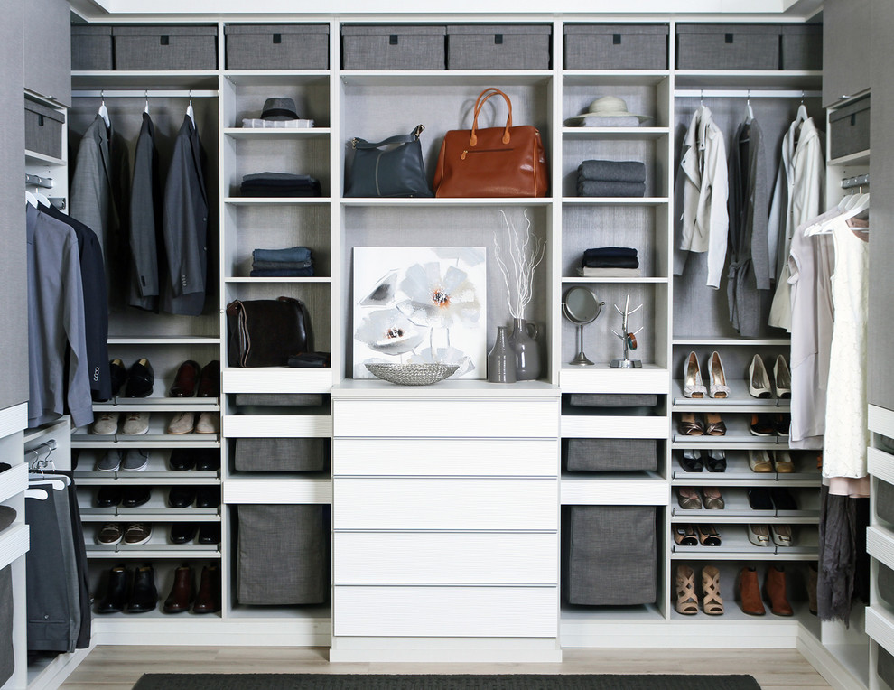 Trendy gender-neutral light wood floor and beige floor walk-in closet photo in Miami with flat-panel cabinets and white cabinets